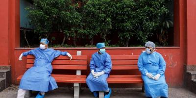 Health workers wearing Personal Protective Equipment (PPE) sit on a bench at a crematorium in New Delhi, India, June 24, 2020. Photo: Reuters/Anushree Fadnavis