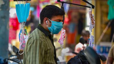 A man wearing face mask walks past a shop displaying colourful face masks at Gandhi Nagar textile-cloth wholesale market, on May 28. Photo: PTI