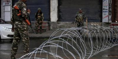 Indian security forces personnel stand guard next to concertina wire laid across a road during restrictions after the government scrapped special status for Kashmir, in Srinagar, August 7, 2019. Photo: Reuters/Danish Ismail
