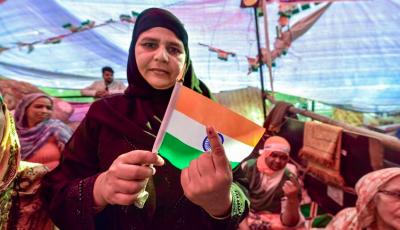 A protester, holding a tricolour, shows her ink-marked finger after casting vote for the Delhi Assembly elections, at the site of their agitation against the Citizenship Act, in Shaheen Bagh | PTI
