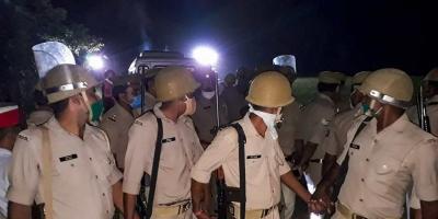 Police personnel during the cremation of a 19-year-old Dalit woman who was brutally gang-raped two weeks ago, in the wee hours, in Hathras district, Wednesday, September 30, 2020. Photo: PTI