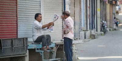 Locals sit in front of closed shops during the shutdown in Srinagar on Thursday, September 26. Photo: PTI