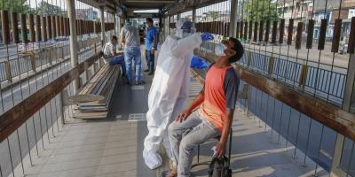 A health worker wearing a PPE kit collects a sample from a man via Rapid Antigen kit for COVID-19 test, at BRTS bus terminal in Ahmedabad, Friday, September 11, 2020. Photo: PTI