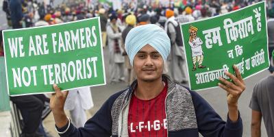 A farmer holds placards during a protest march against the Centre's agri-laws at the Delhi-Meerut Expressway in New Delhi, December 11, 2020. Photo: PTI/Kamal Singh