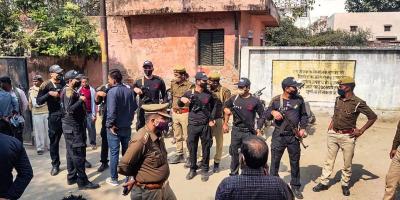 Security personnel stand guard during post-mortem of two minor Dalit girls, who were found dead in a field on Wednesday evening, near Baburaha village in Unnao district, Thursday, Feb. 18, 2021. Another minor who was found in critical condition is undergoing treatment at a hospital. Photo: PTI.