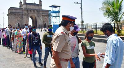 People queue up as they wait for their turn to undergo a temperature test before entering the Gateway of India, in Mumbai, Sunday, April 04, 2021. Photo: PTI