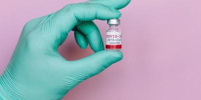 An illustrative photograph showing a person holding a vial marked 'COVID-19 vaccine'. Photo: Nataliya Vaitkevich/Pexels