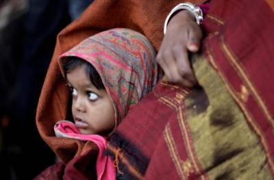 A girl wrapped in a shawl looks on as she waits along with her mother for a train at a railway station on a cold winter morning in New Delhi, India. Photo: Reuters/Saumya Khandelwal
