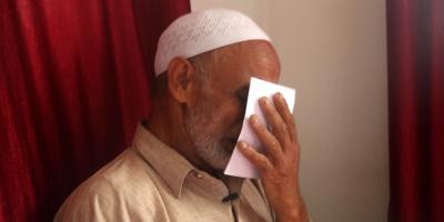 Imran's father kissing the picture of his son while tears fall from his eyes. Photo: Muneeb-ul-Islam