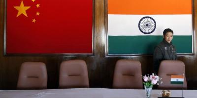 A man walks inside a conference room with Indian and Chinese flags in the background. Photo: Reuters/Adnan Abidi/File photo