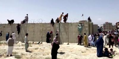 People climb a barbed wire wall to enter the airport in Kabul, Afghanistan August 16, 2021, in this still image taken from a video. Photo: Reuters TV/via Reuters/File Photo