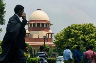 A lawyer in traditional robes, with the Supreme Court in the background. Photo: PTI