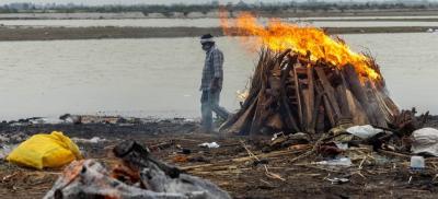 Representative image. A man walks past burning pyres with people who died from COVID-19 in Uttar Pradesh, May 6, 2021. Photo: Reuters/Danish Siddiqui