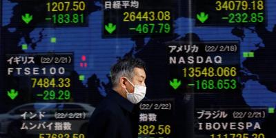 FILE PHOTO: A man wearing a protective mask, amid the coronavirus disease (COVID-19) outbreak, walks past an electronic board displaying Japan's Nikkei index and various countries' stock market index prices outside a brokerage in Tokyo, Japan, February 22, 2022. Photo: Reuters/Kim Kyung-Hoon.