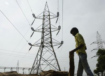 A man stands in front of an electric pylon installed at a power house in the northern Indian city of Allahabad, July 31, 2012. Photo: Reuters/Jitendra Prakash/Files