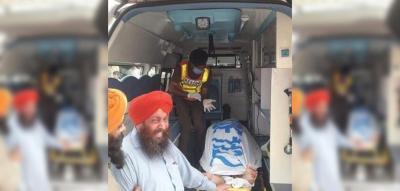Two Sikh men beside the body of one of the victims of the May 15 attack as it is taken away. Photo: Twitter