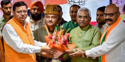 Uttarakhand chief minister Pushkar Singh Dhami and state BJP President Madan Kaushik present a bouquet to former AAP leader Colonel Ajay Kothiyal (retd) after he joined BJP, in Dehradun, Tuesday, May 24, 2022. Photo: PTI