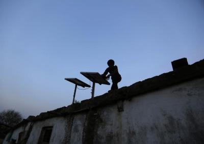 A boy dusts off a solar panel installed on the rooftop of his house on the outskirts of Ahmedabad October 27, 2014. Photo: Reuters/Amit Dave/Files
