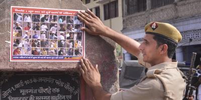 A policeman sticks a poster of those accused of communal violence in Kanpur, Monday, June 6, 2022. Photo: PTI