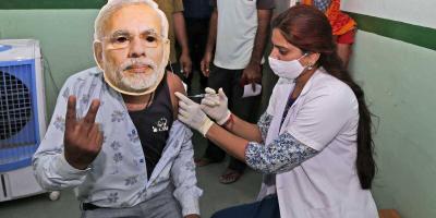 A health worker gives a COVID-19 vaccine dose to a beneficiary wearing a face mask of Prime Minister Narendra Modi during a vaccination drive in Beawar, Friday, Sept. 17, 2021. Photo: PTI/File