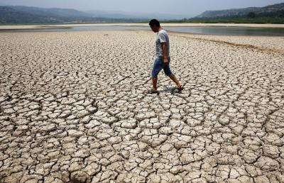 A man walks through the dried-up bed of a reservoir in Sanyuan county, Shaanxi province July 30, 2014. Photo: REUTERS/Stringer/Files