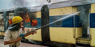 A firefighter tries to douse a fire in a train, set by people protesting against Centres Agnipath scheme, at Kulharia railway station, in Bhojpur, June 17, 2022. Photo: PTI
