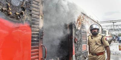 A policeman stands near a train-coach set ablaze by a mob at the Secunderabad Railway Station in protest against the Central government's Agnipath scheme in Hyderabad, June 17, 2022. Photo: PTI