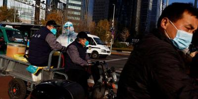 A worker in a protective suit rides on an electric tricycle on a street during morning rush hour, following the outbreak of the coronavirus disease (COVID-19), in the Central Business District (CBD) in Chaoyang District, Beijing, China November 21, 2022. REUTERS/Tingshu Wang