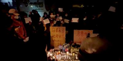People hold signs and light candles during a vigil held for the victims of the Urumqi fire, in Shanghai, China November 26, 2022 in this picture obtained from a social media video. Photo: Gao Ming/via Reuters