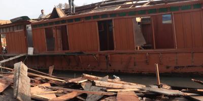 The owner of a houseboat stand on its broken structure. Photo: Sameer Hussain.