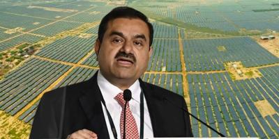Gautam Adani. In the background is an image of solar panels in a section of the Adani website advertising Adani Green Energy Limited. 