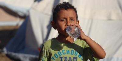 A five-year-old boy drinks bottled water delivered by UNICEF in the Khan Younis camp in Gaza. Photo: UNICEF/Eyad El Baba 
